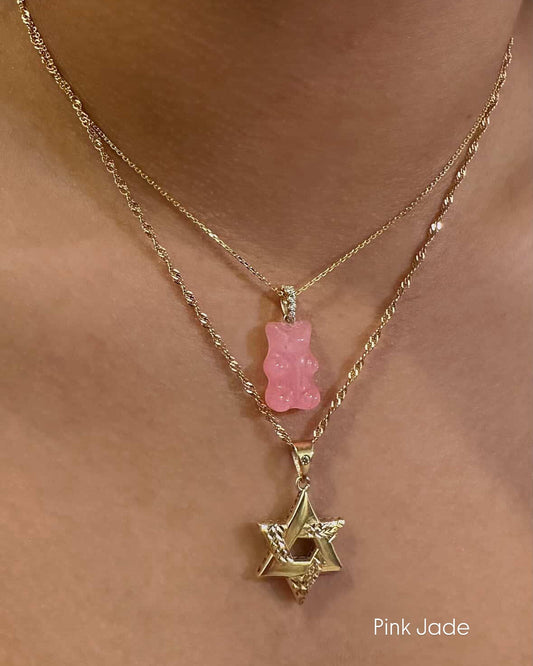 Necklace with pink gummy bear and gold star of David pendant on a person's neck.